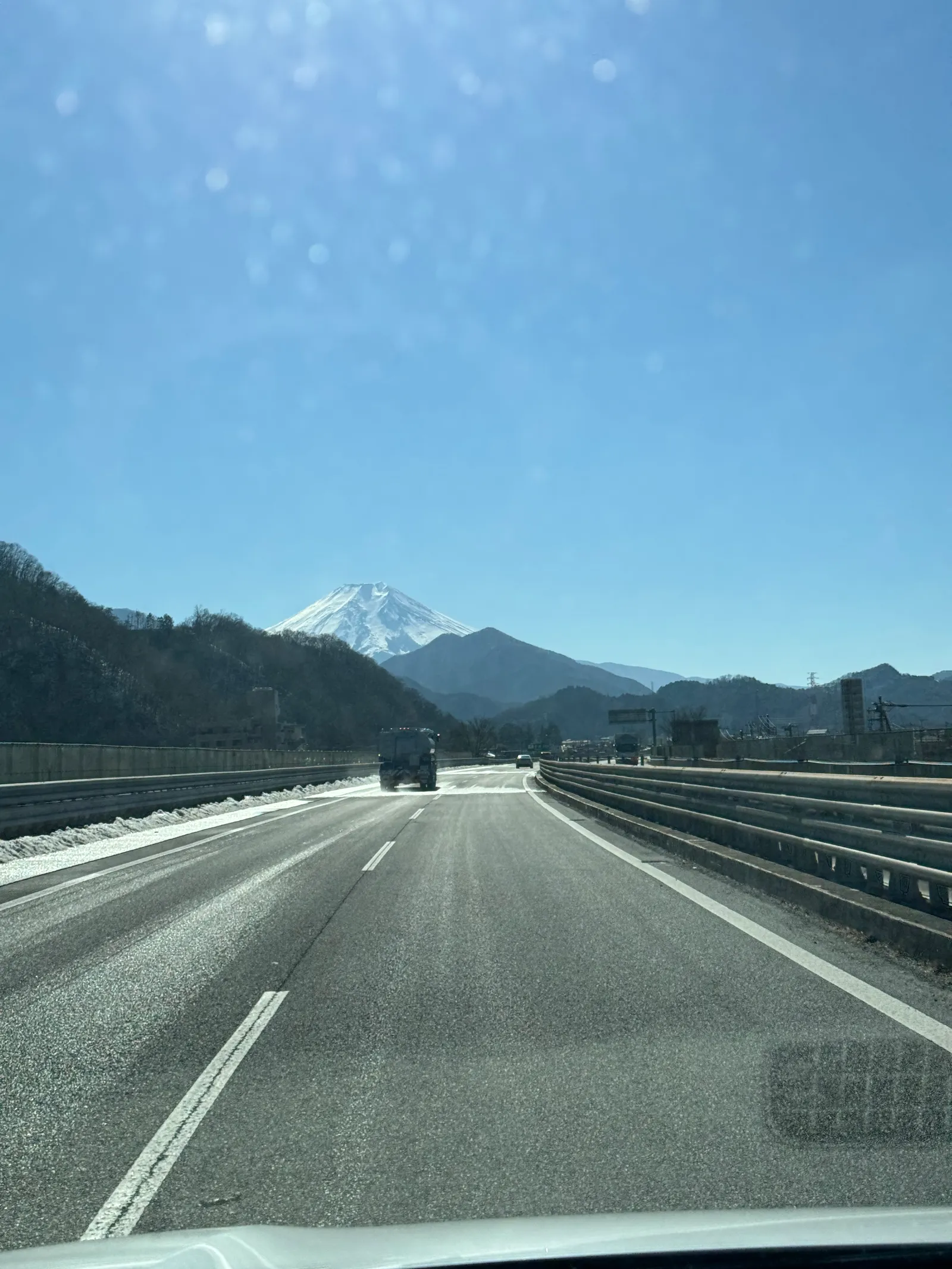 Snow-capped Mount Fuji seen down a highway from a car, Chuo Expressway, Japan