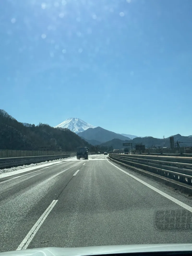 Snow-capped Mount Fuji seen down a highway from a car, Chuo Expressway, Japan