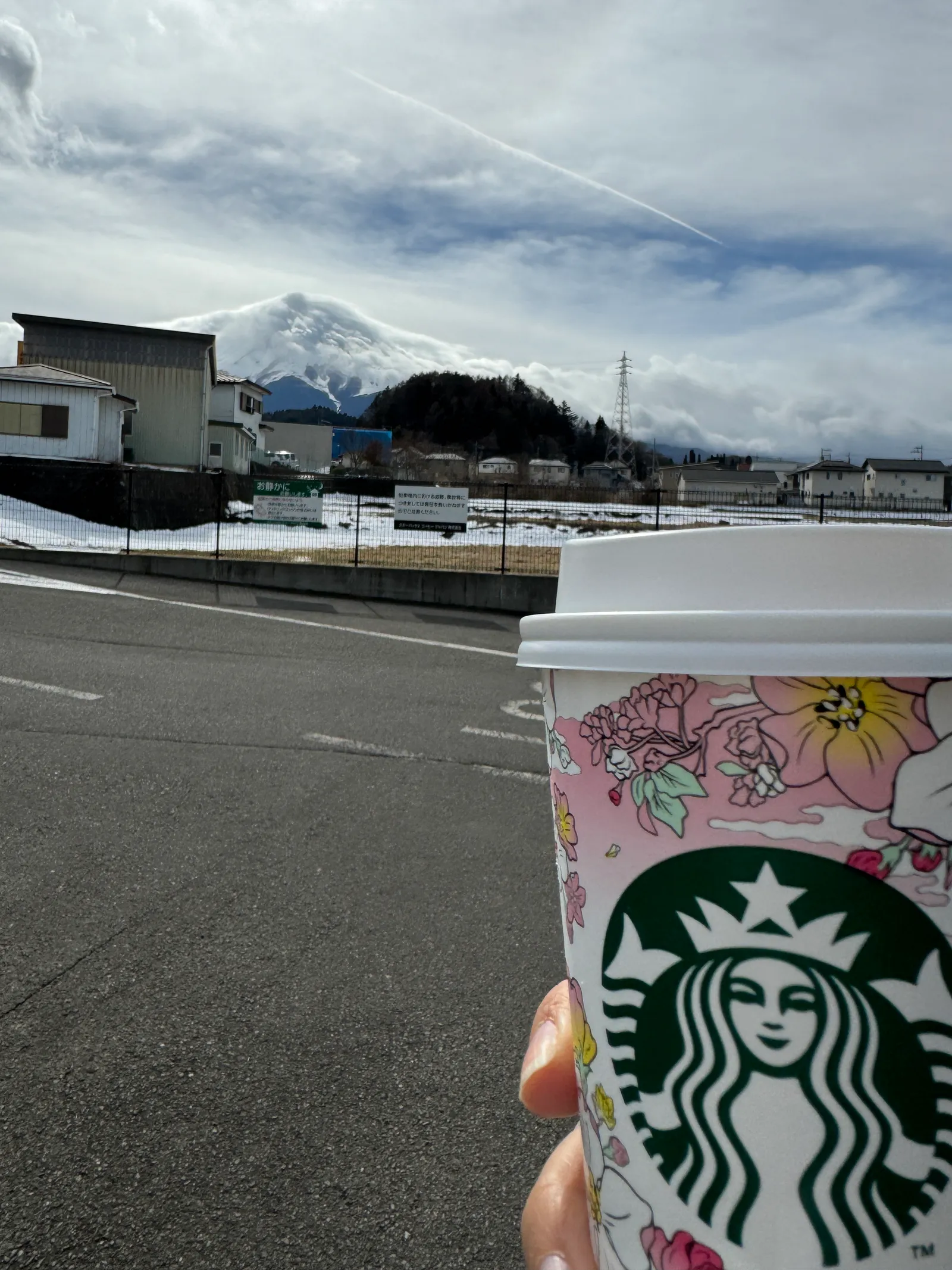 Starbucks cup held up in front of Mount Fuji with snow and cloud