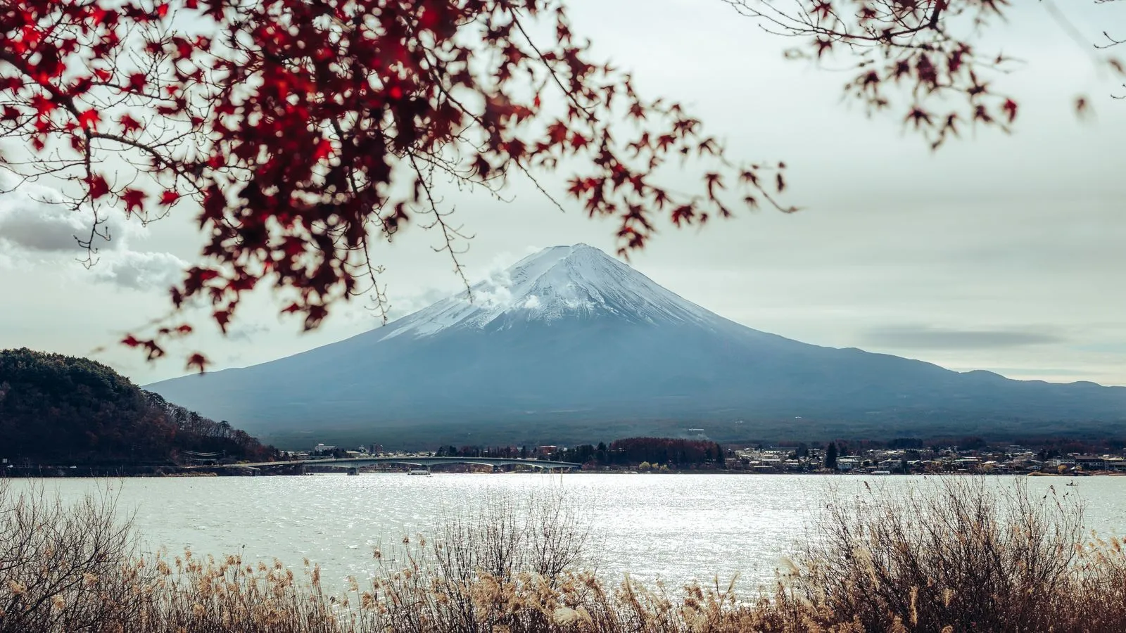 Mt Fuji across Lake Kawaguchi framed by red maple leaves, the lake bridge on the left