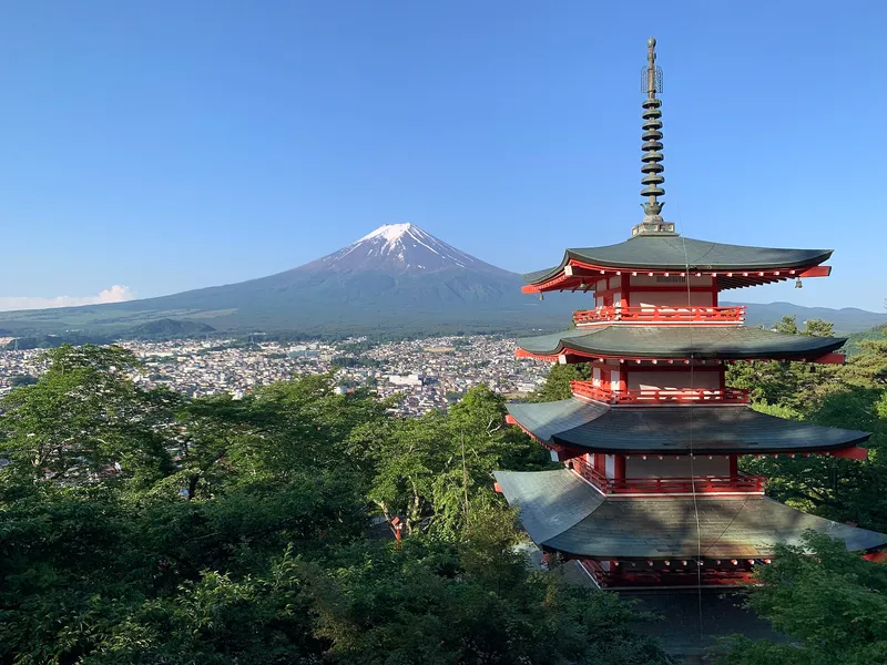 Chureito Pagoda among green summer trees, Mt Fuji with a little snow under a clear blue sky