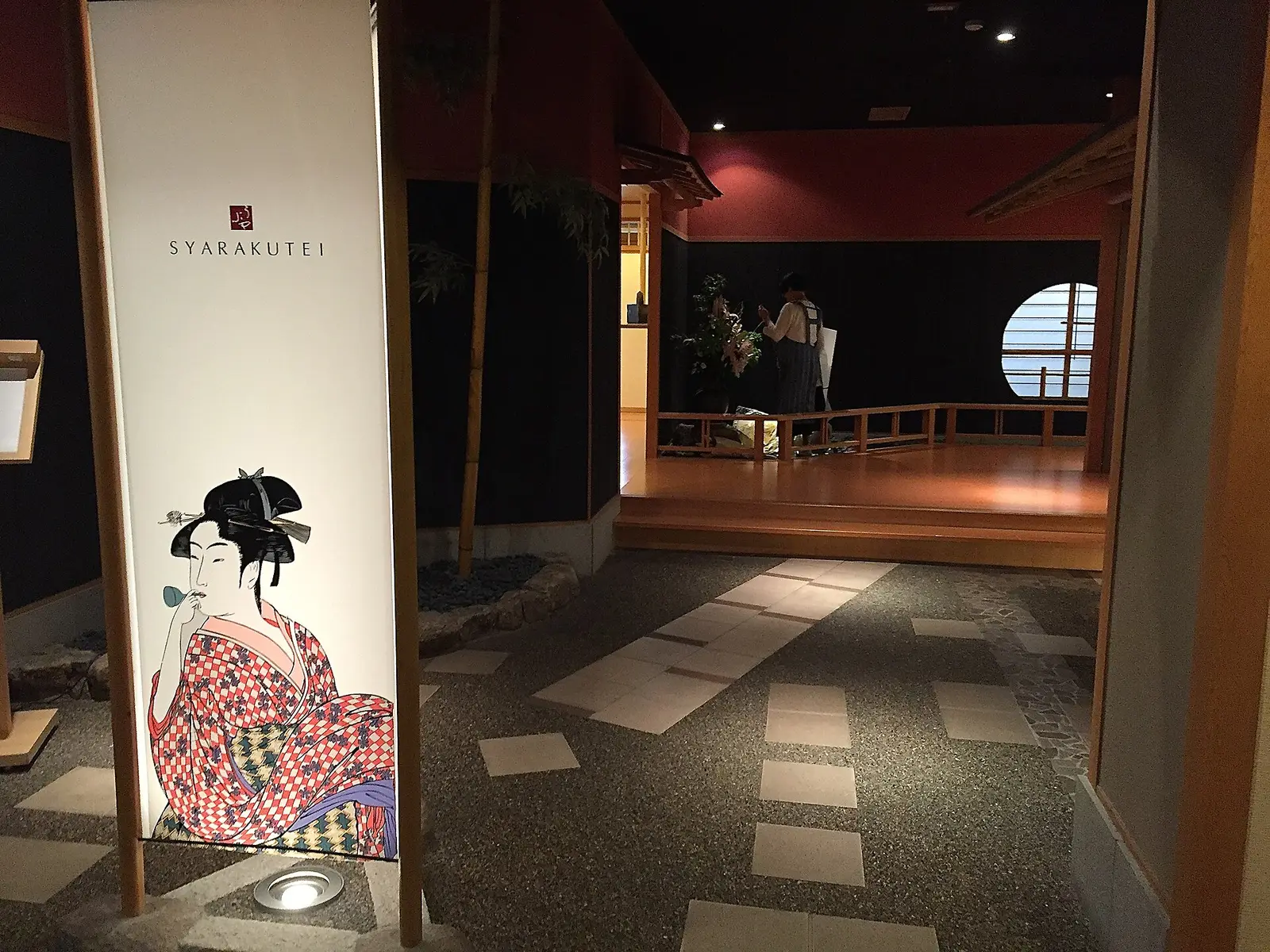 Dim entrance to a ryokan restaurant with an ukiyo-e panel and stepping stones