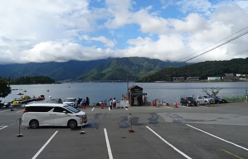 Lakeside car park and pedal boats on Lake Kawaguchi, the lake bridge in the distance