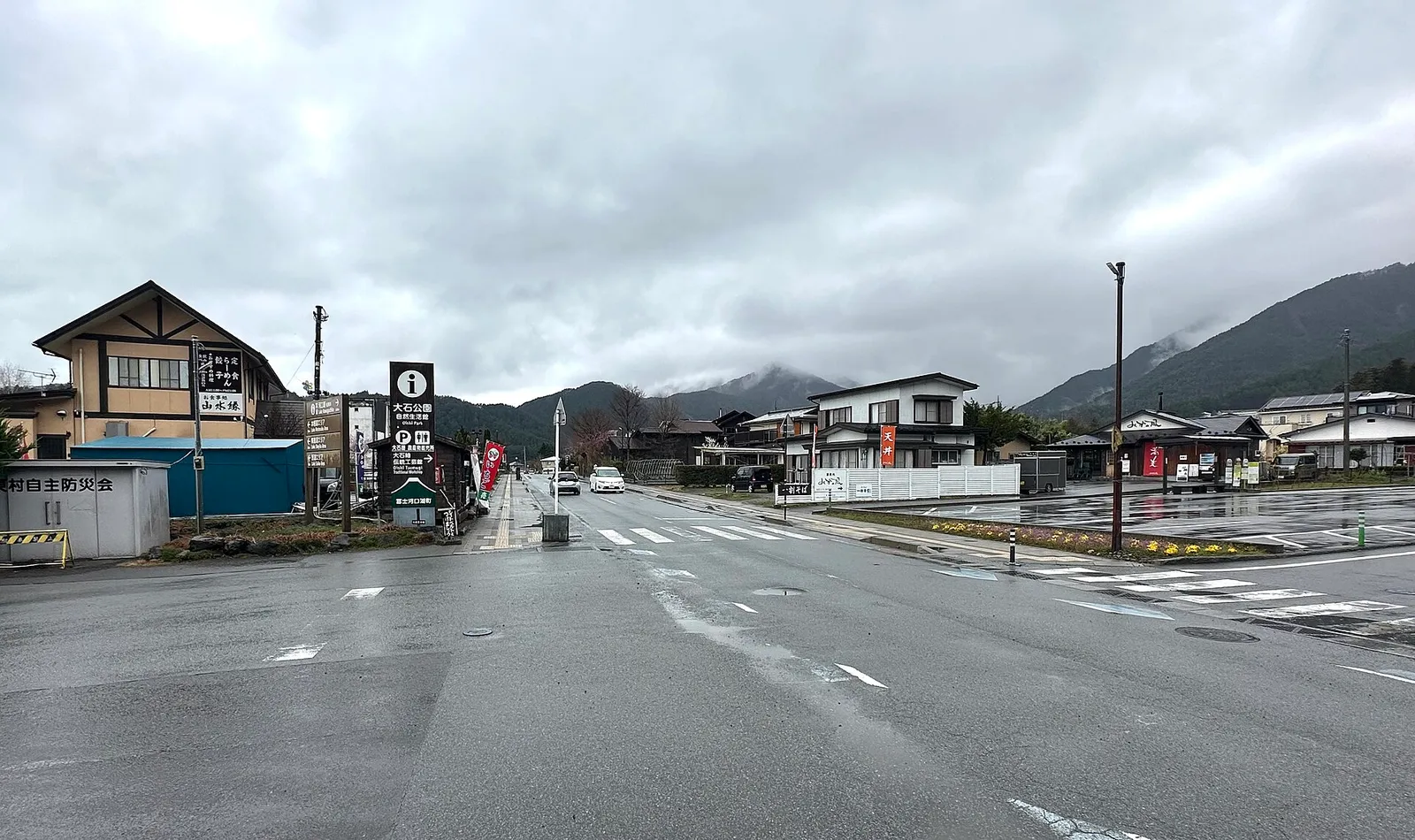 Rainy crossroads in Oishi with signs for the park, mountains in cloud