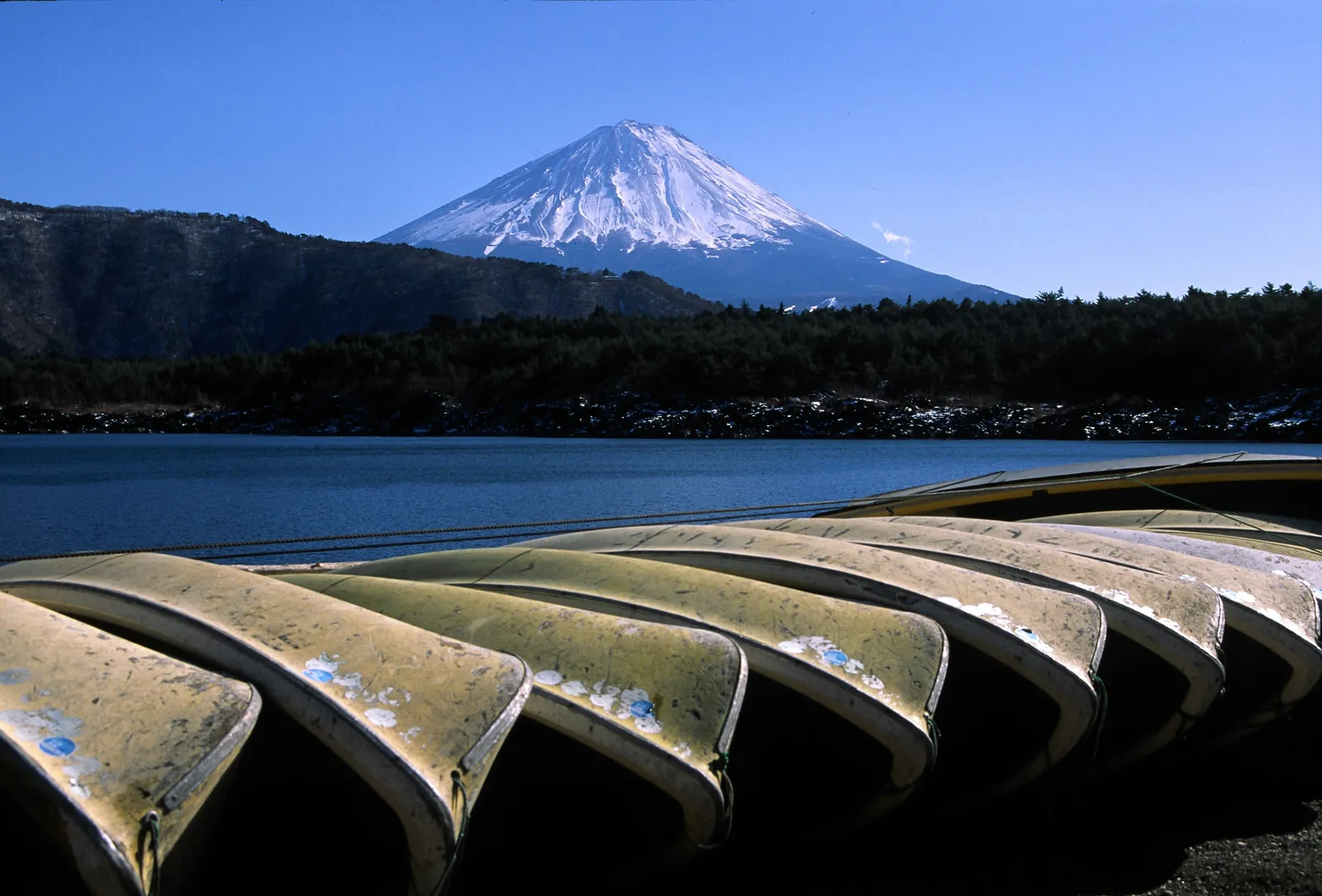 Rowing boats pulled up on the shore of Lake Saiko, snow-capped Mt Fuji behind