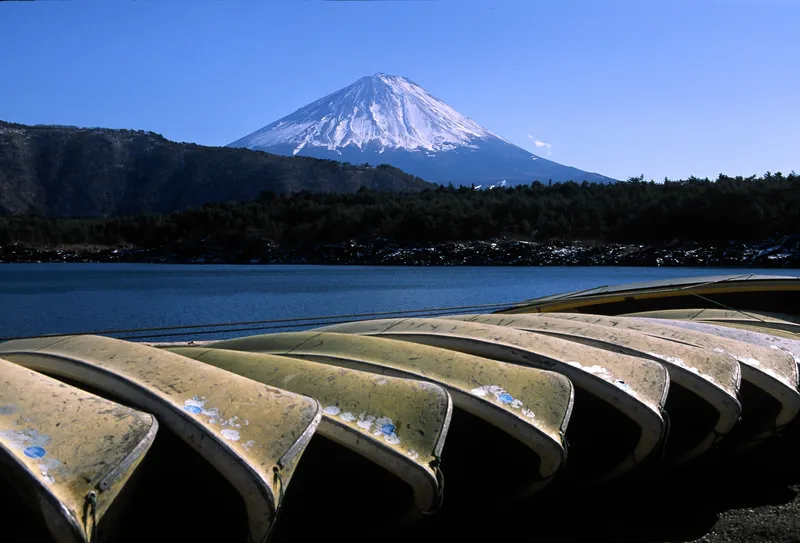 Rowing boats pulled up on the shore of Lake Saiko, snow-capped Mt Fuji behind