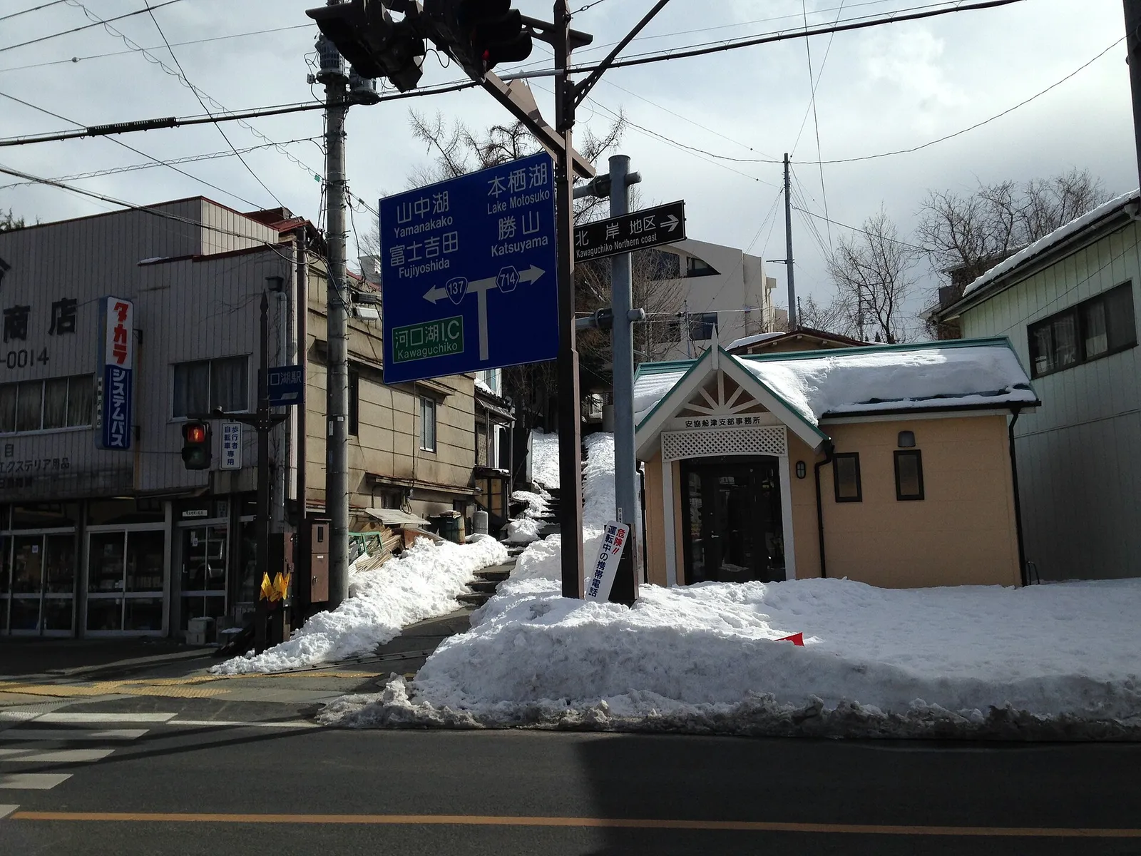 Snowy street corner with road signs to Yamanakako, Fujiyoshida and Lake Motosu