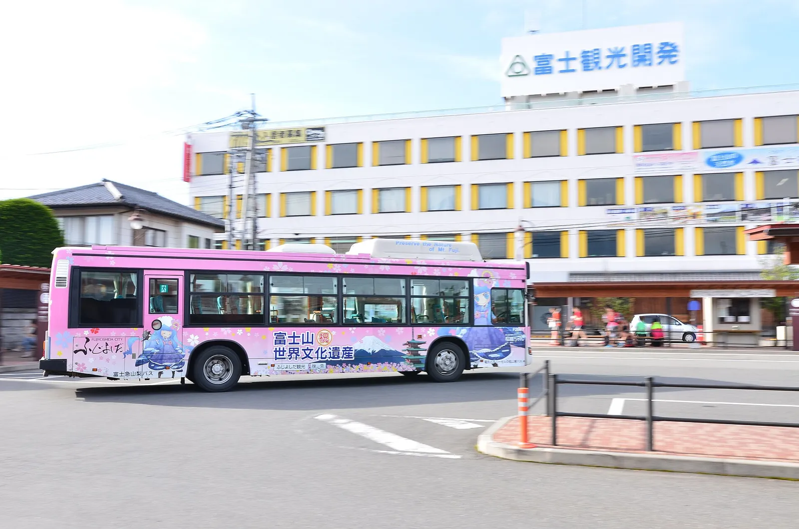 Pink Mt Fuji World Heritage bus passing the Fuji Kanko building