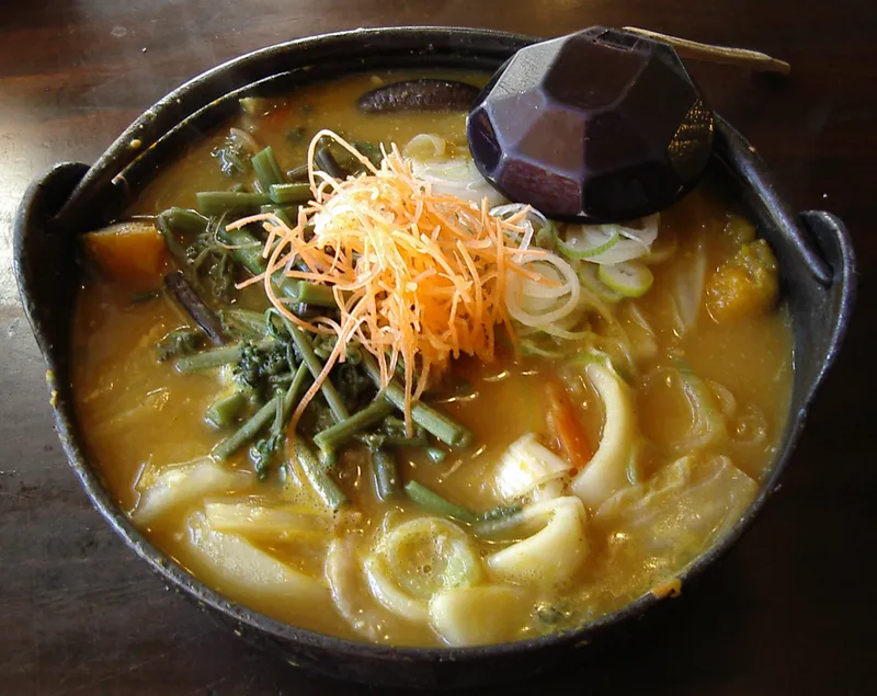 Hoto: thick flat noodles with pumpkin and mountain vegetables in miso broth, in an iron pot