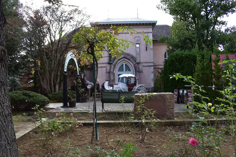Pink stone building with a white carriage and horse statue, Kawaguchiko Music Forest Museum